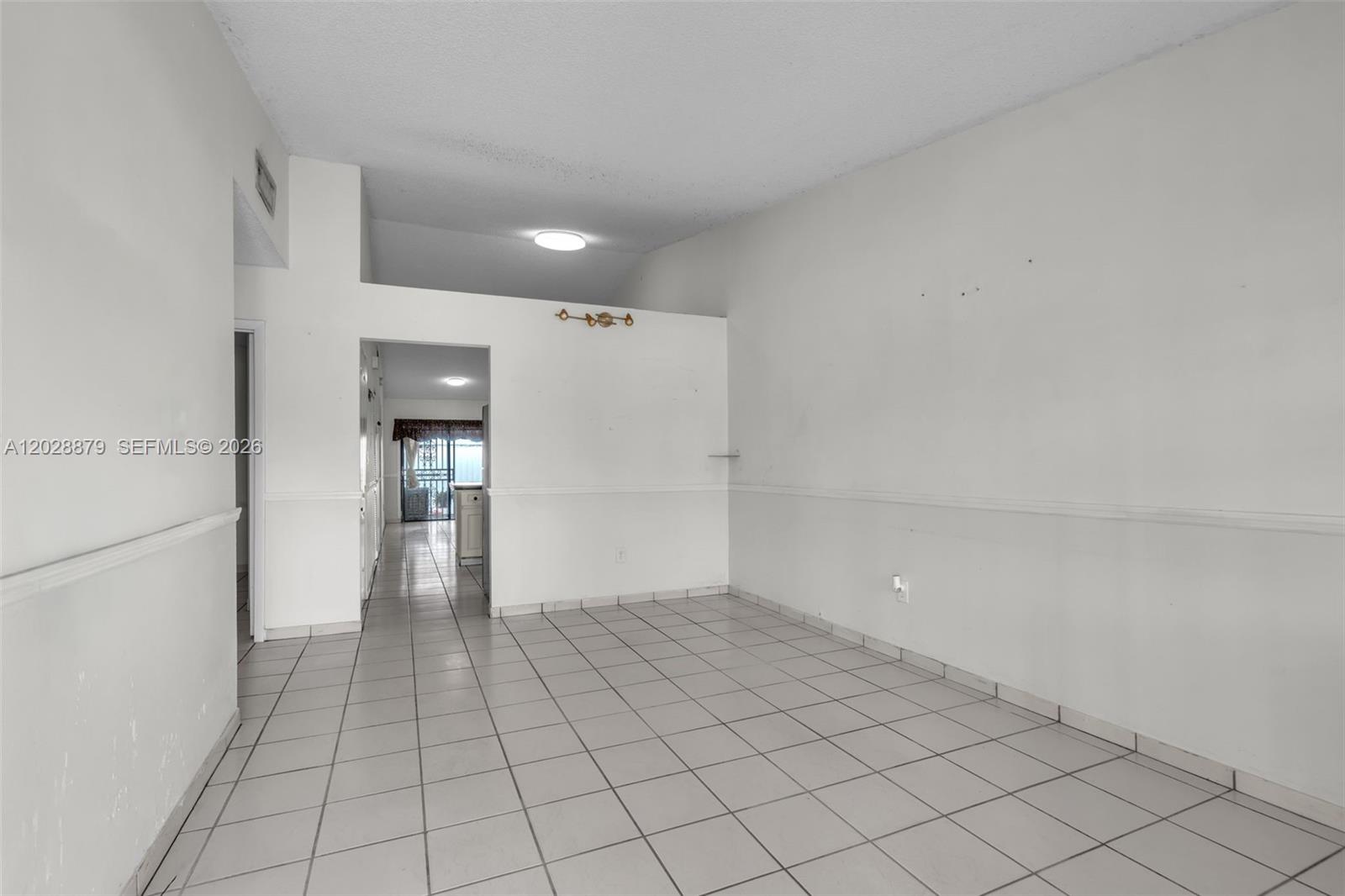 An empty room features white walls, a chair rail, and light-colored floor tiles — 8805 NW 114th Ter, Hialeah Gardens FL 33018, HIALEAH GARDENS, FL