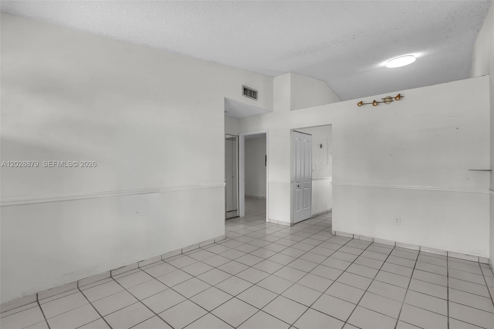 An empty room features white walls, a chair rail, and light-colored square floor tiles — 8805 NW 114th Ter, Hialeah Gardens FL 33018, HIALEAH GARDENS, FL