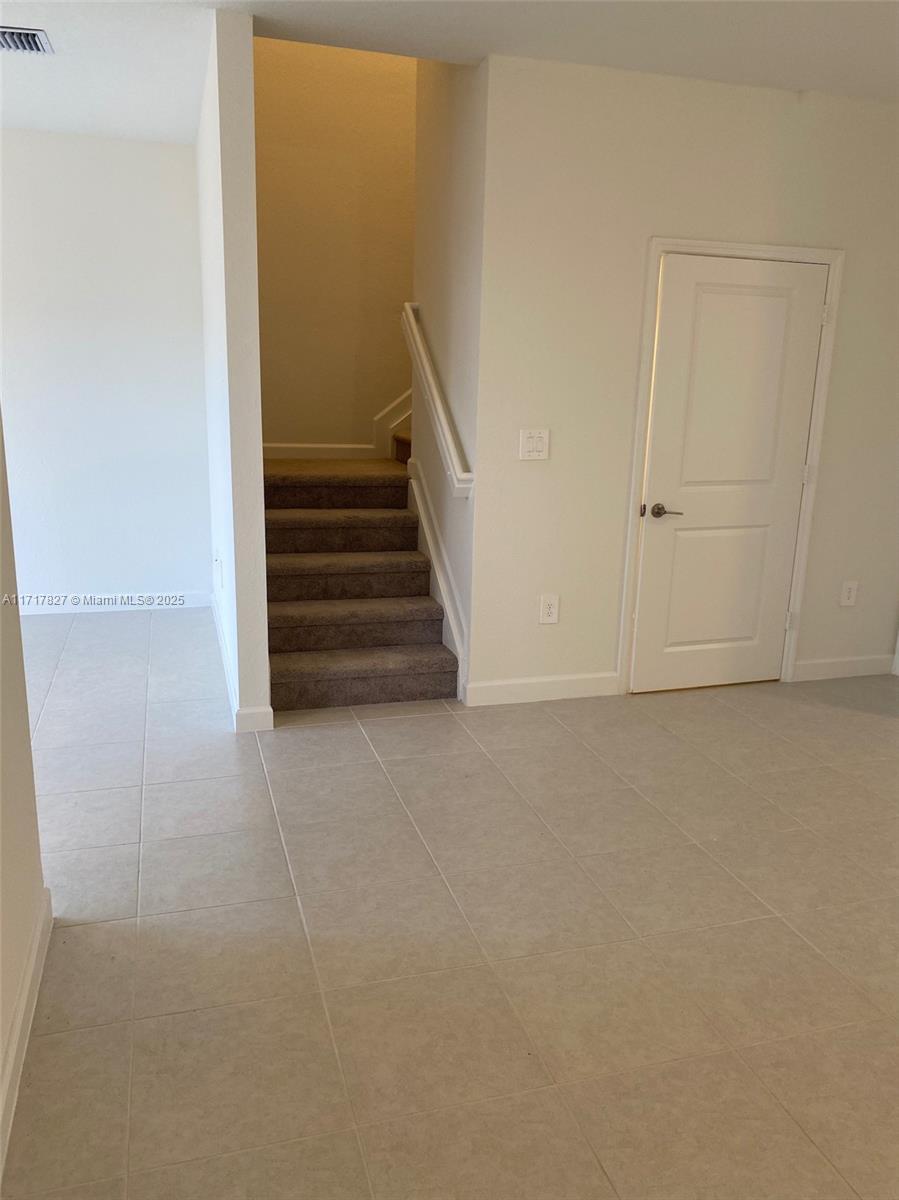 An interior view shows a tiled room with a carpeted staircase and a closed door — 12623 NW 24th Ave # 12623, Miami FL 33167, MIAMI, FL