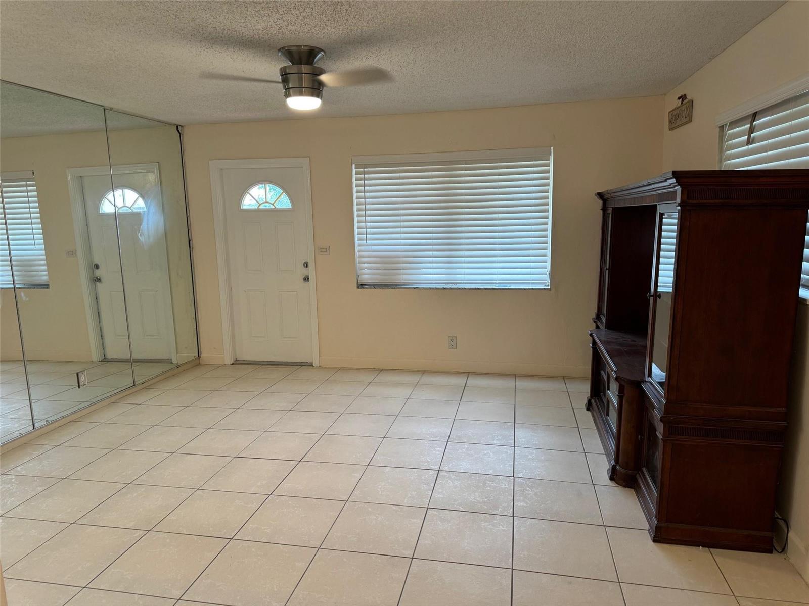 A room with light-colored tile flooring, a ceiling fan, mirrored closet doors, and a hutch — 4564 NW 16th Avenue, Tamarac FL 33309, TAMARAC, FL