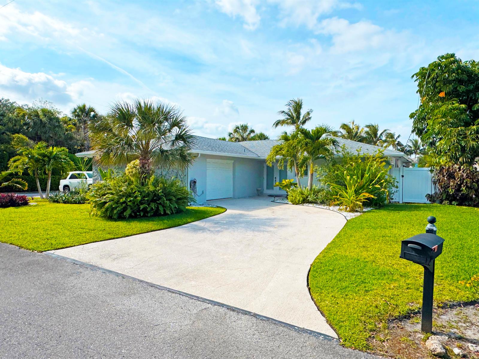 A single-story house with a concrete driveway, palm trees, and a green lawn — 106 Periwinkle Drive, Hypoluxo FL 33462, HYPOLUXO, FL