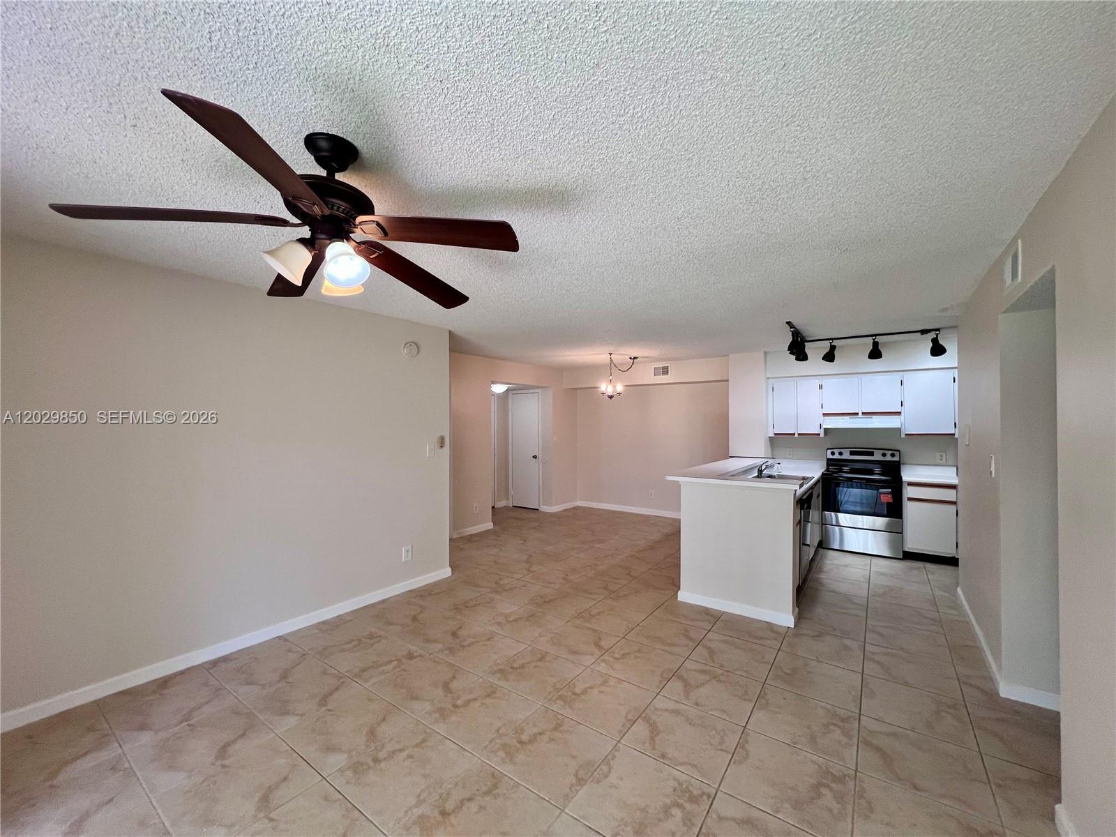 An open-concept kitchen and living area features tile flooring, a ceiling fan, and white cabinetry — 640 S Park Rd # 4, Hollywood FL 33021, HOLLYWOOD, FL