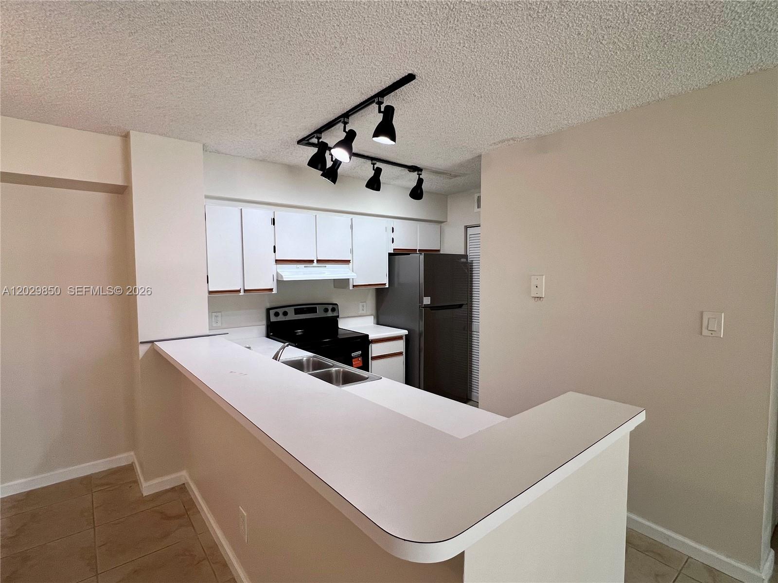 A kitchen features white cabinets, a breakfast bar, and a track lighting fixture — 640 S Park Rd # 4, Hollywood FL 33021, HOLLYWOOD, FL