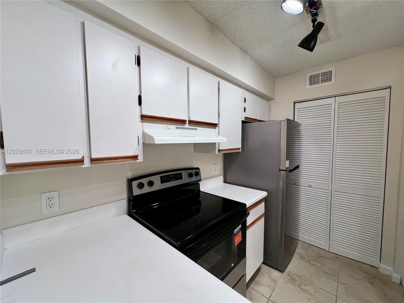 A kitchen features white cabinets, a black electric stove, a gray refrigerator, and tile flooring — 640 S Park Rd # 4, Hollywood FL 33021, HOLLYWOOD, FL