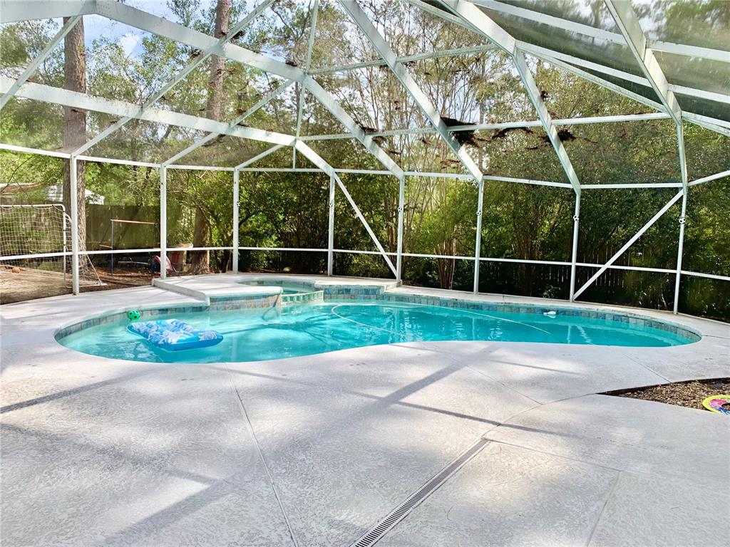 A swimming pool and attached spa are enclosed within a screened-in lanai — 2219 NW 17TH AVENUE, GAINESVILLE, FL
