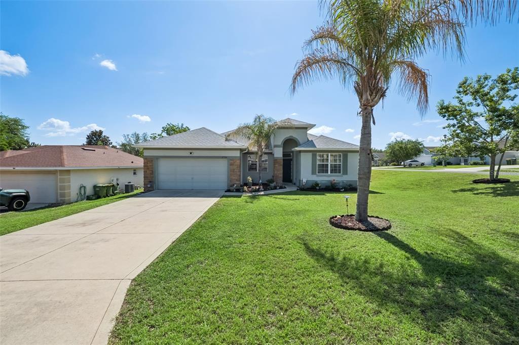 A single-story house with a two-car garage, a palm tree, and a large front lawn — 2720 SAVANNAH DRIVE, LEESBURG, FL