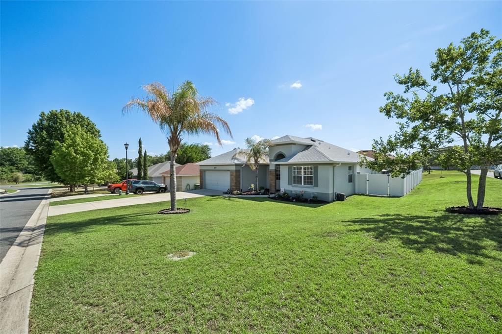 A single-story house with a two-car garage and a large front lawn under blue skies — 2720 SAVANNAH DRIVE, LEESBURG, FL