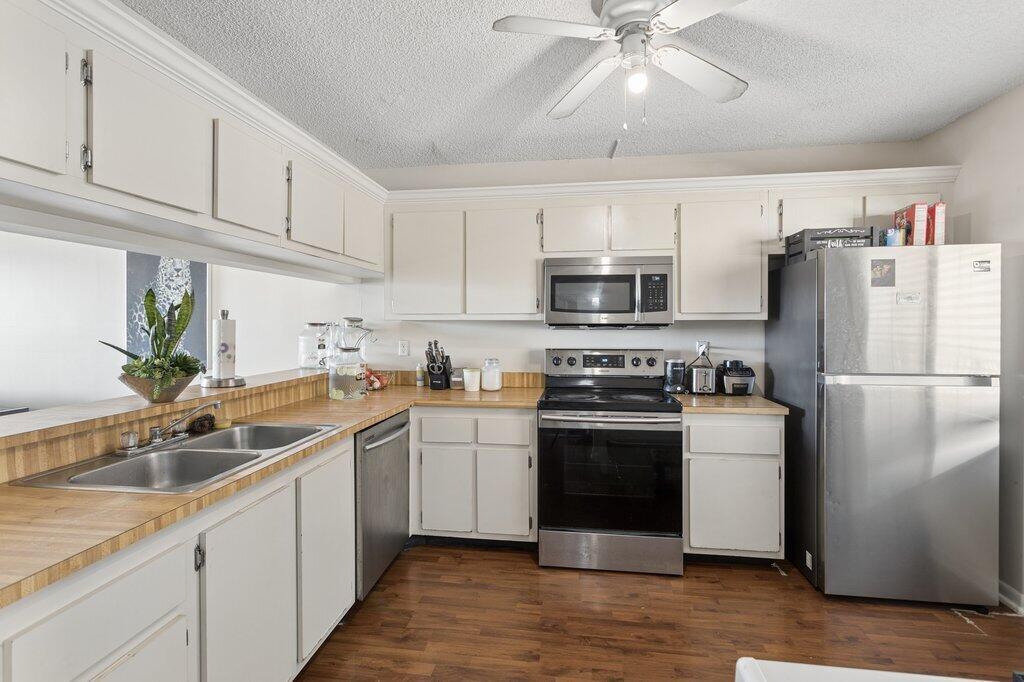 A kitchen with white cabinets, wood-look flooring, laminate countertops, and stainless steel appliances — 8030 Hampton Boulevard # 404, North Lauderdale FL 33068, NORTH LAUDERDALE, FL