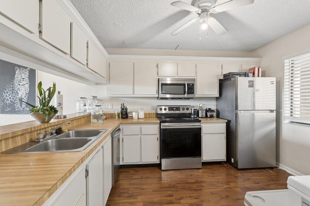 A kitchen with white cabinets, stainless steel appliances, wood-look flooring, and a laminate countertop — 8030 Hampton Boulevard # 404, North Lauderdale FL 33068, NORTH LAUDERDALE, FL