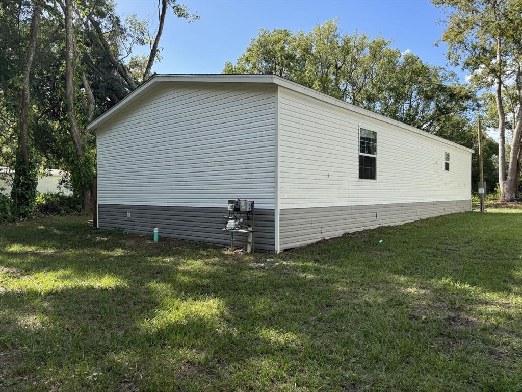 A side view of a white and gray manufactured home exterior on a grassy lot — 9536 MERTON STREET, NEW PORT RICHEY, FL
