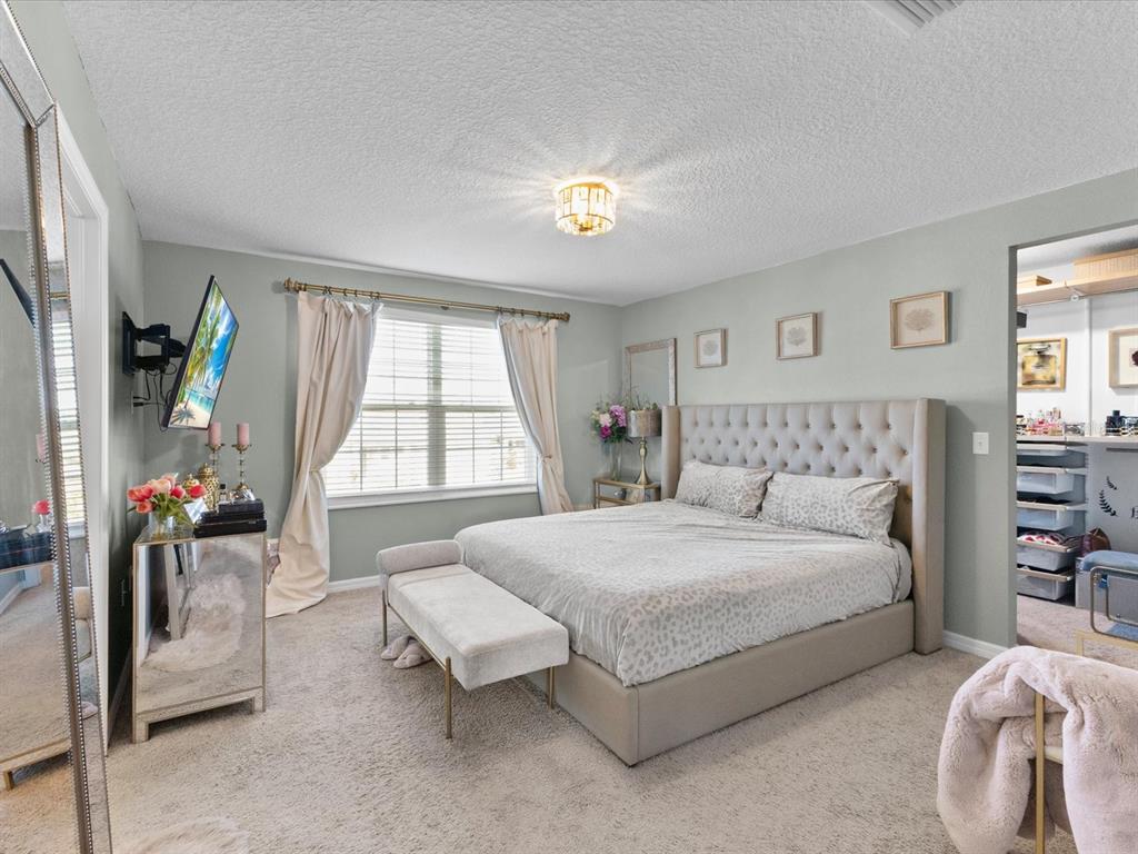 A bedroom features a tufted headboard, mirrored furniture, and a walk-in closet — 5372 FEZ COURT, BROOKSVILLE, FL