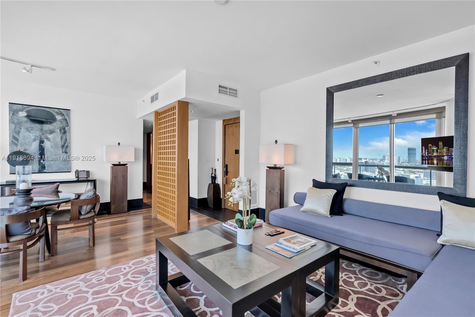 A living room features a blue sofa, a coffee table, and a large wall mirror — 101 20th St # 2504, Miami Beach FL 33139, MIAMI BEACH, FL