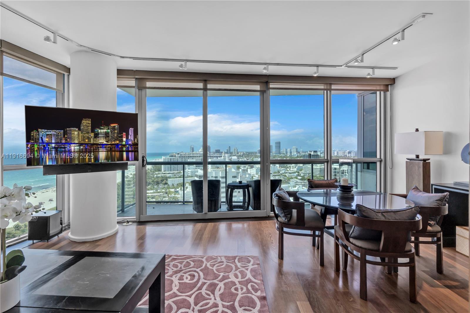 A dining area with a glass table and city views through floor-to-ceiling windows — 101 20th St # 2504, Miami Beach FL 33139, MIAMI BEACH, FL