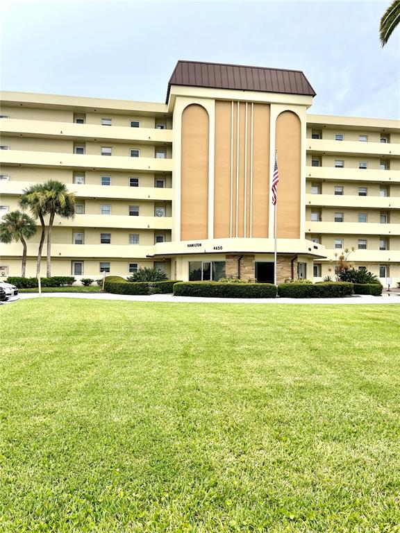 A multi-story apartment building with a central entrance and a large front lawn — 4650 COVE CIRCLE UNIT 402, ST PETERSBURG, FL
