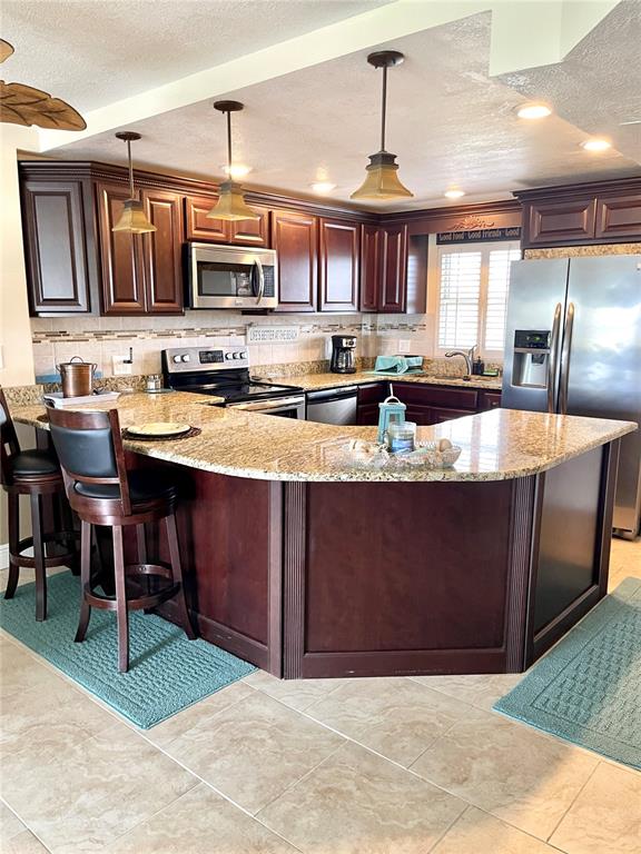 A kitchen features dark wood cabinets, granite countertops, a stainless steel refrigerator, and pendant lighting — 4650 COVE CIRCLE UNIT 402, ST PETERSBURG, FL