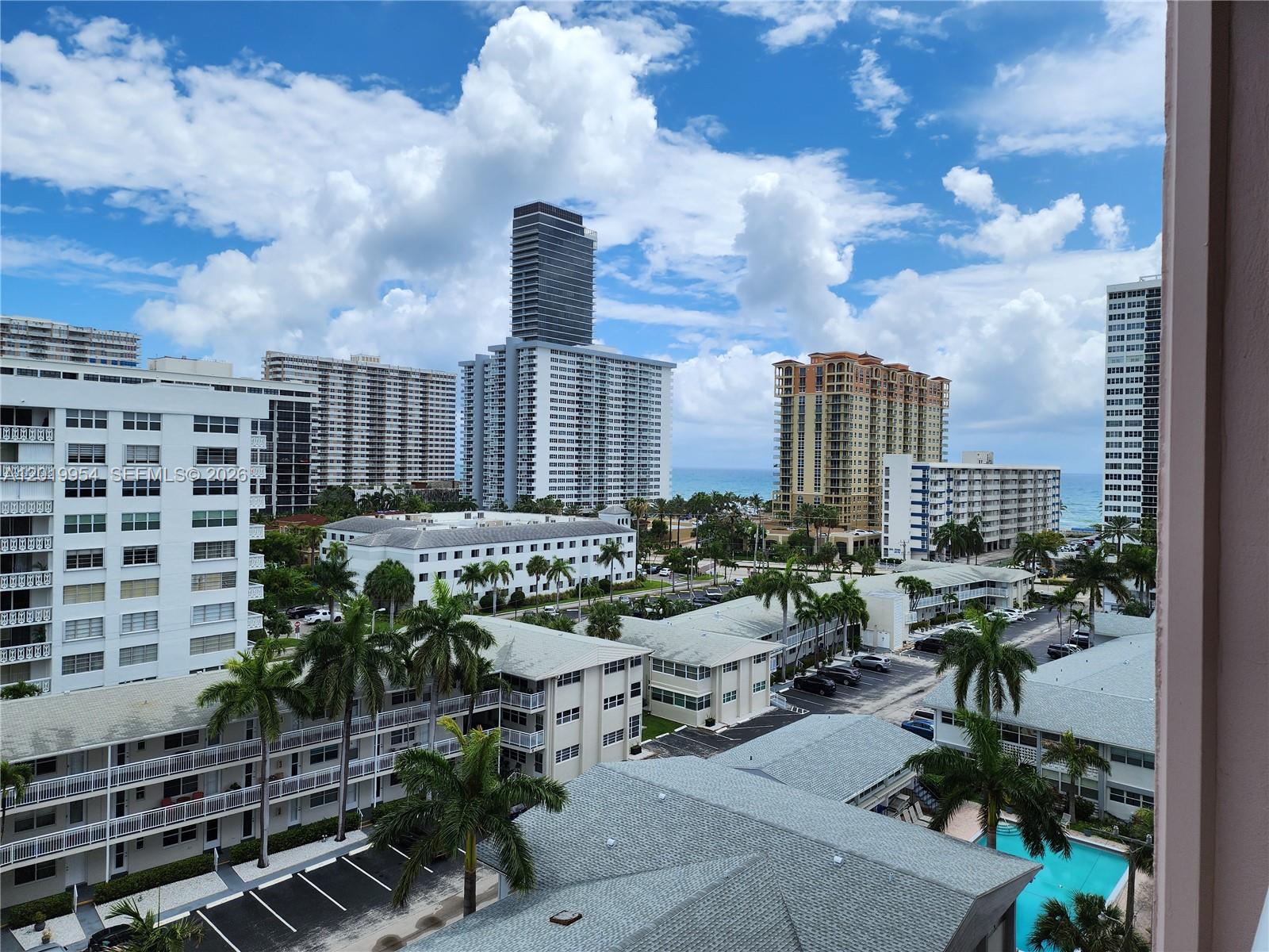 An elevated view of a coastal city featuring high-rise buildings, palm trees, and a pool — 3161 S Ocean Dr # 903, Hallandale Beach FL 33009, HALLANDALE BEACH, FL