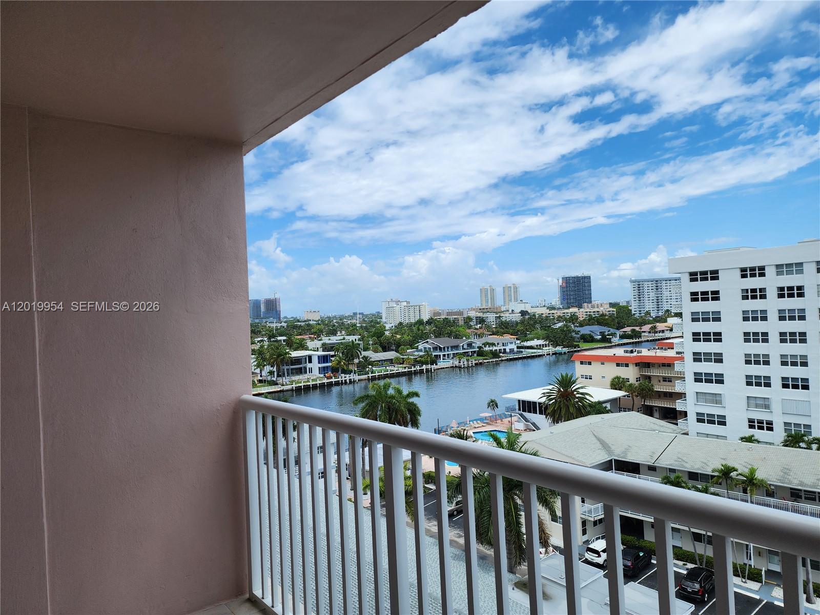 A balcony overlooks a canal, palm trees, and surrounding residential buildings under a cloudy sky — 3161 S Ocean Dr # 903, Hallandale Beach FL 33009, HALLANDALE BEACH, FL