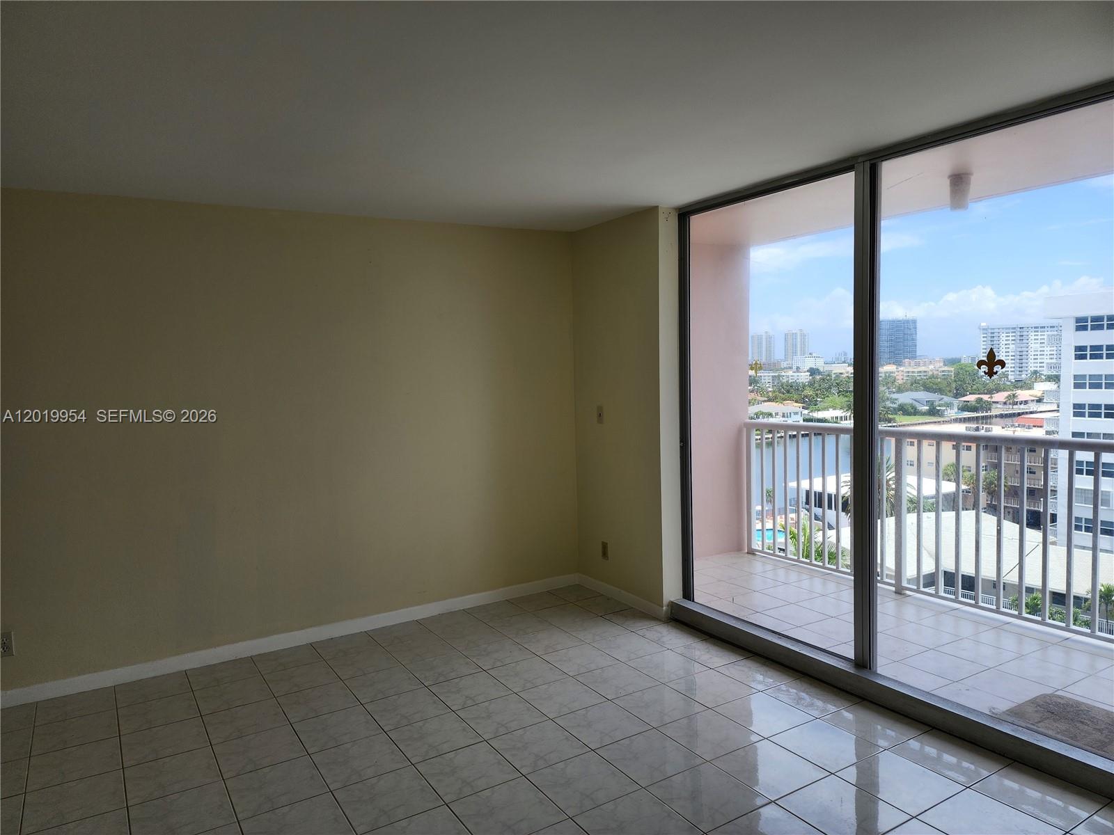 An empty room with tiled floors features a large sliding glass door opening to a balcony — 3161 S Ocean Dr # 903, Hallandale Beach FL 33009, HALLANDALE BEACH, FL