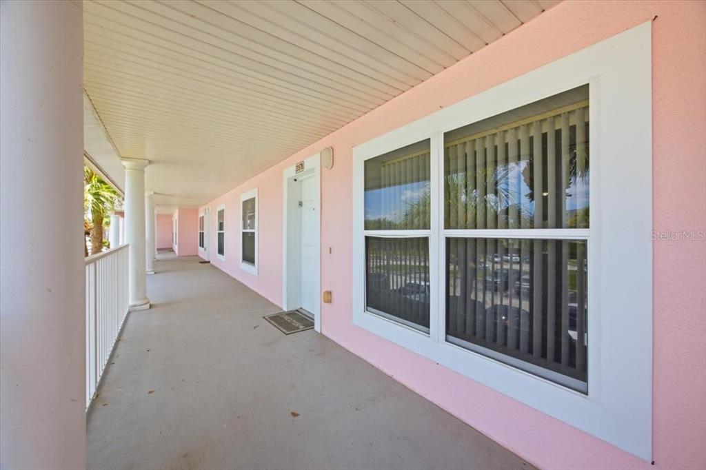 A pink exterior wall features a long covered walkway with white columns and windows — 3157 SUN LAKE COURT UNIT B, KISSIMMEE, FL