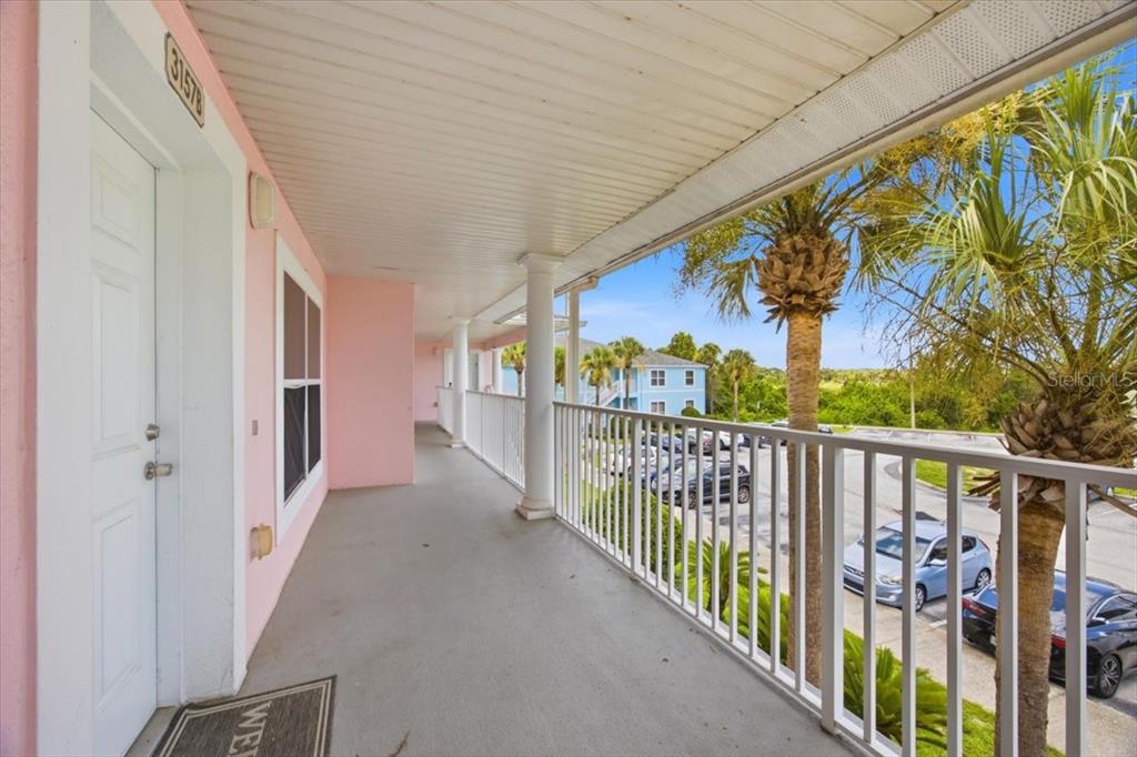 A pink exterior balcony features a white railing, a white door, and a palm tree — 3157 SUN LAKE COURT UNIT B, KISSIMMEE, FL
