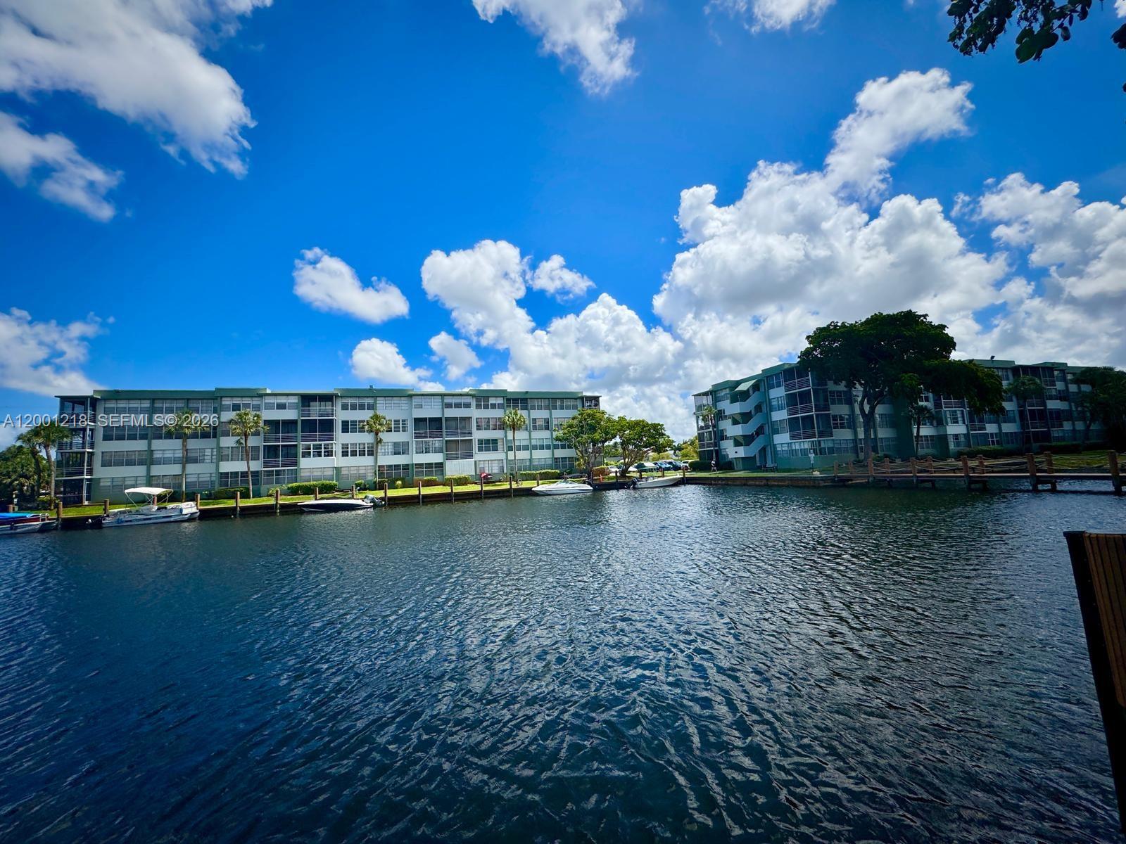 A canal separates two multi-story apartment buildings with boat docks under a blue sky — 2741 Taft St # 404, Hollywood FL 33020, HOLLYWOOD, FL