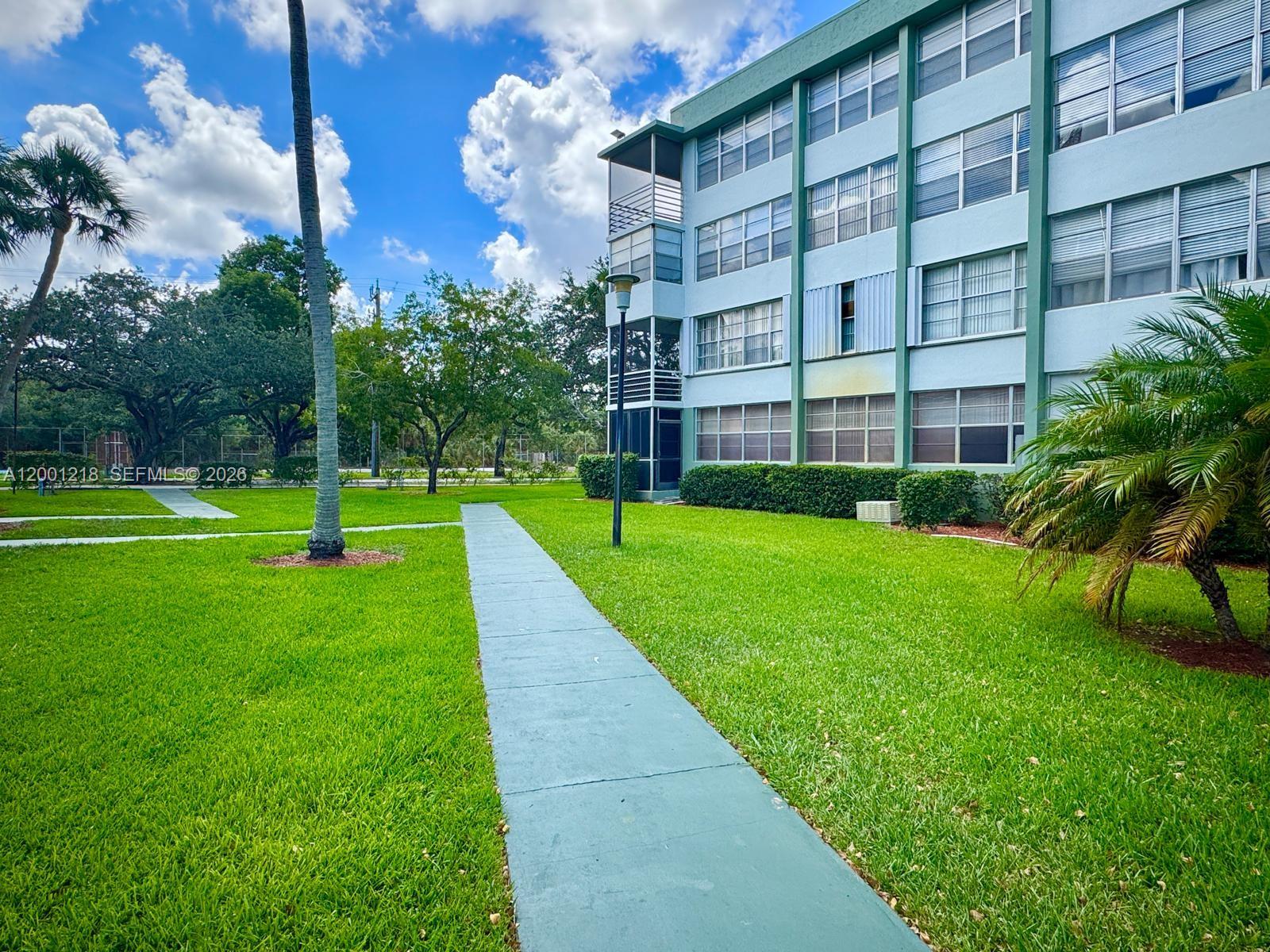 A multi-story apartment building exterior with a paved walkway and green lawn — 2741 Taft St # 404, Hollywood FL 33020, HOLLYWOOD, FL