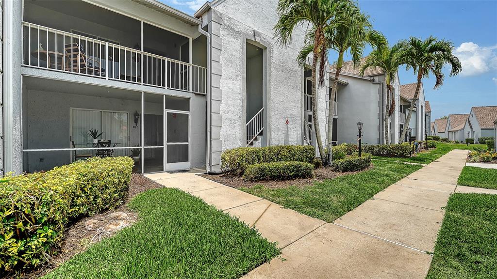 A two-story apartment building features a screened-in ground floor patio and a second-story balcony — 6611 STONE RIVER ROAD UNIT 103, BRADENTON, FL