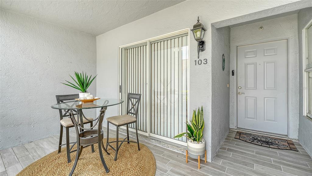 A patio features a glass-topped table with two chairs, a potted plant, and a front door — 6611 STONE RIVER ROAD UNIT 103, BRADENTON, FL