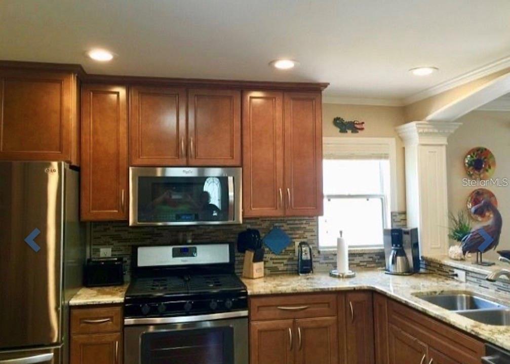A kitchen with wood cabinets, stainless steel appliances, and a stone countertop — 1041 REIDVILLE ROAD, THE VILLAGES, FL