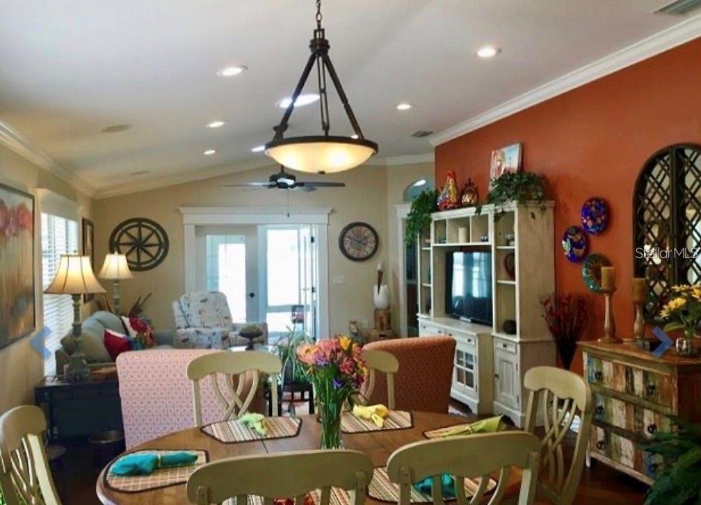 A dining area with a wooden table and chandelier opens into a living room — 1041 REIDVILLE ROAD, THE VILLAGES, FL