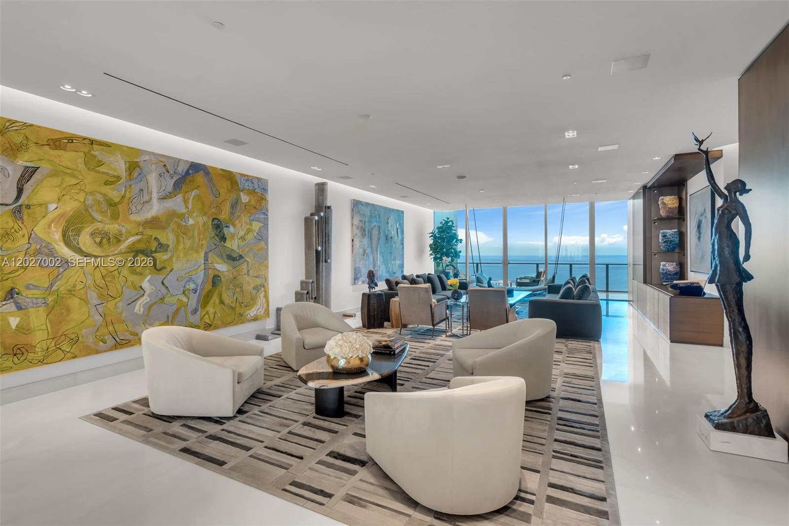A spacious living room features modern furniture, large abstract paintings, and floor-to-ceiling ocean views — 350 Ocean Dr, Key Biscayne FL 33149, KEY BISCAYNE, FL