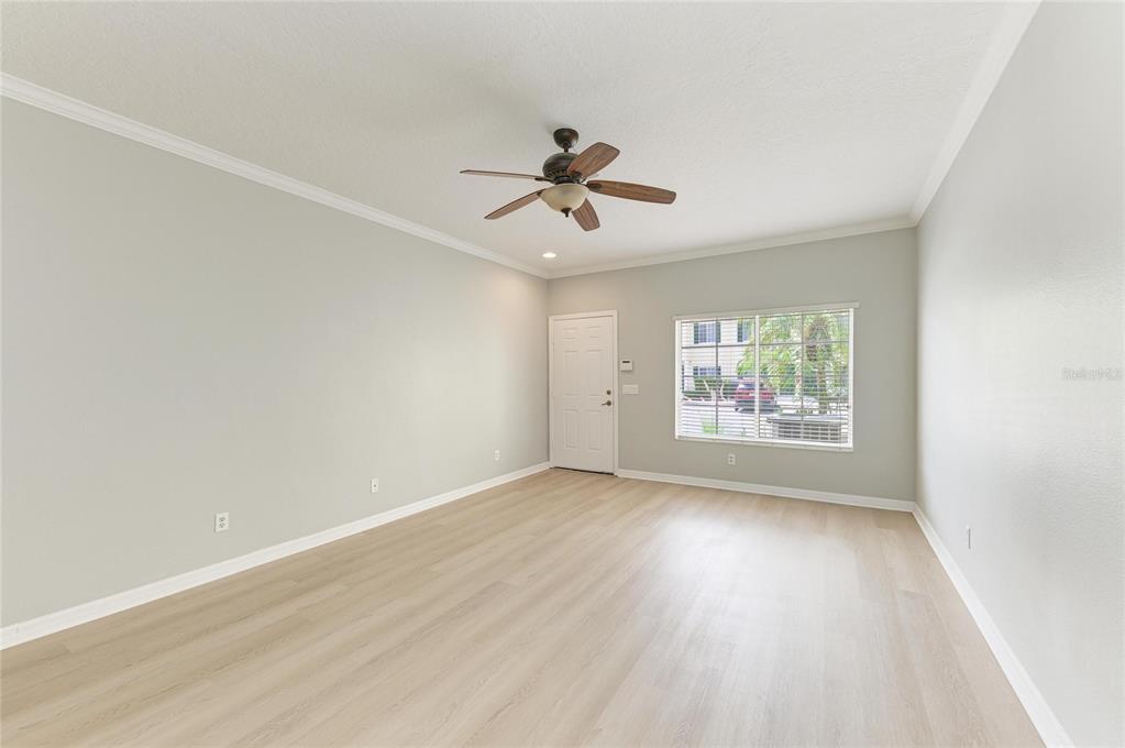 An empty room with light wood-look flooring, a ceiling fan, and a single window — 233 CAPE HARBOUR LOOP UNIT 103, BRADENTON, FL