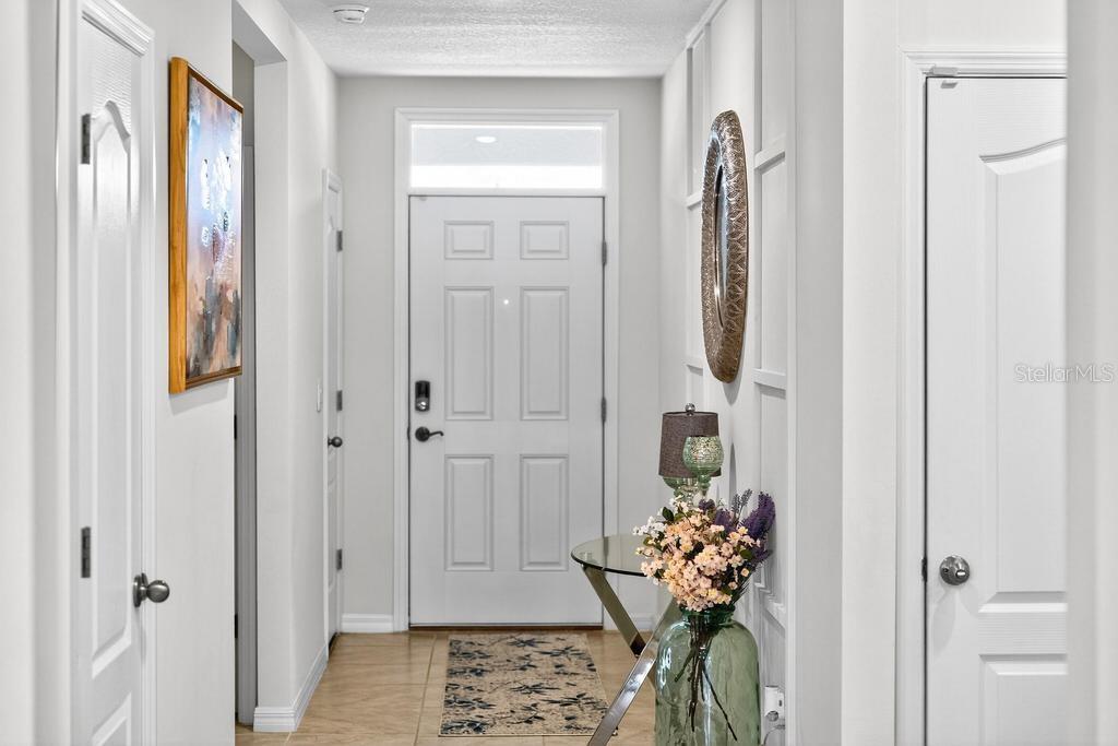 A bright entryway features a white front door, tile flooring, and decorative wall paneling — 33470 ALWAYS DREAMING COURT, SORRENTO, FL
