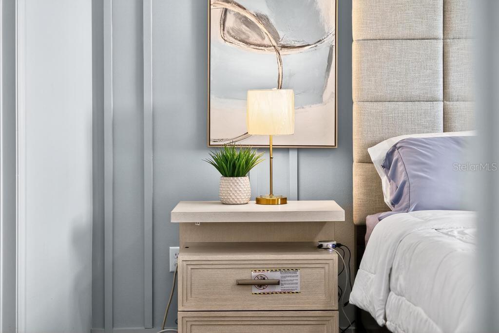A bedside table with a lamp and plant sits next to a tufted headboard — 33470 ALWAYS DREAMING COURT, SORRENTO, FL