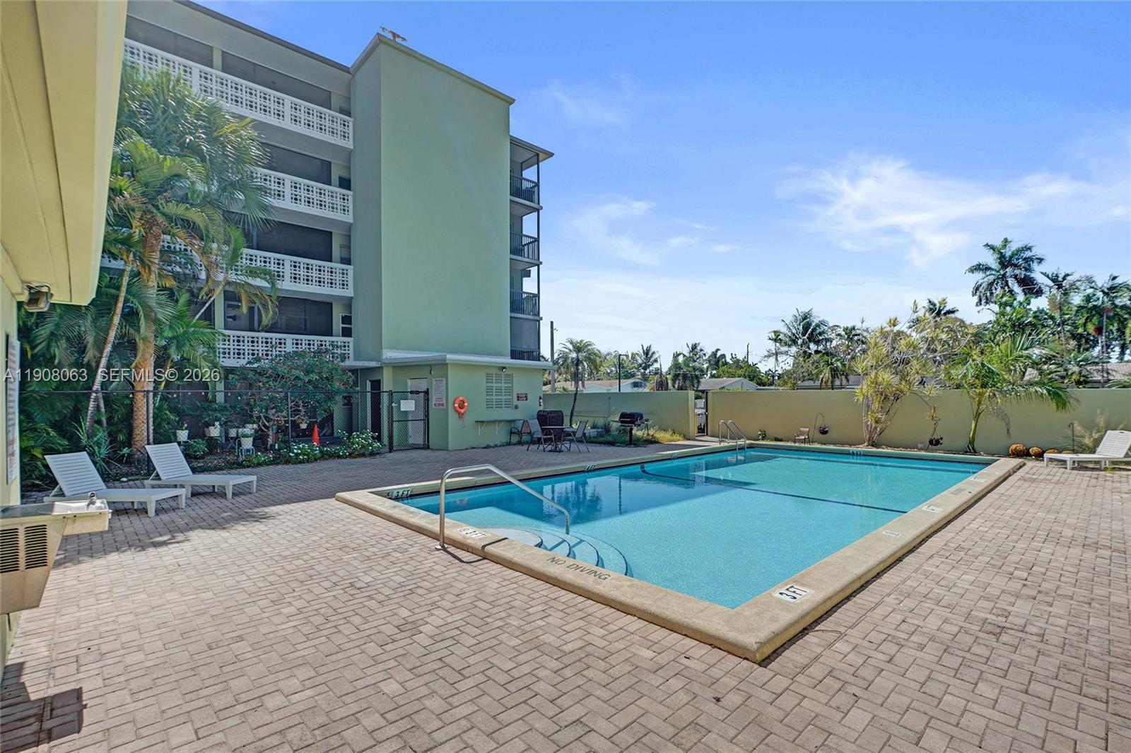 A swimming pool sits on a paved patio beside a multi-story apartment building — 1425 Arthur St # 301A, Hollywood FL 33020, HOLLYWOOD, FL