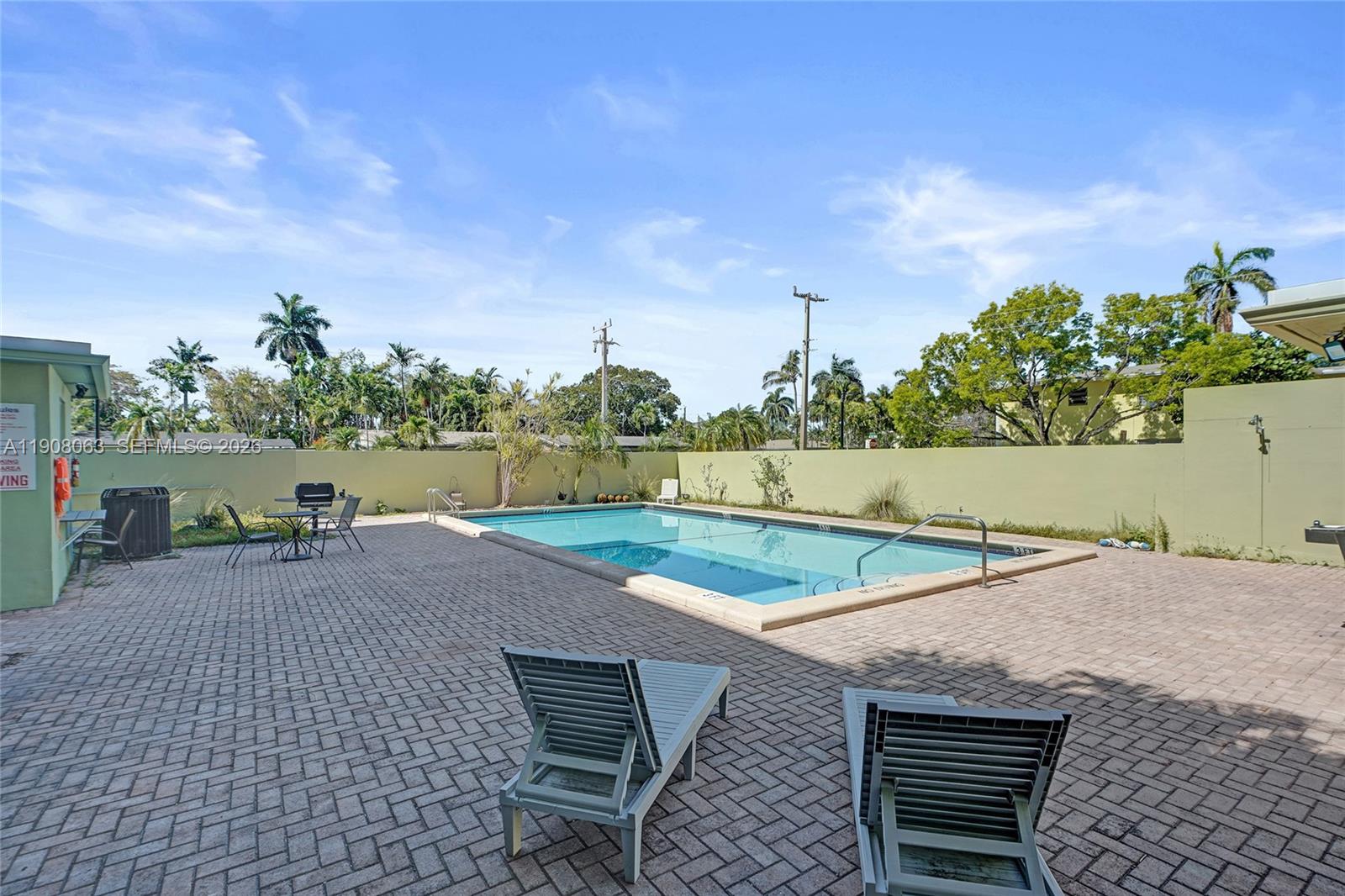 An outdoor swimming pool area features lounge chairs, a patio, and a perimeter wall — 1425 Arthur St # 301A, Hollywood FL 33020, HOLLYWOOD, FL