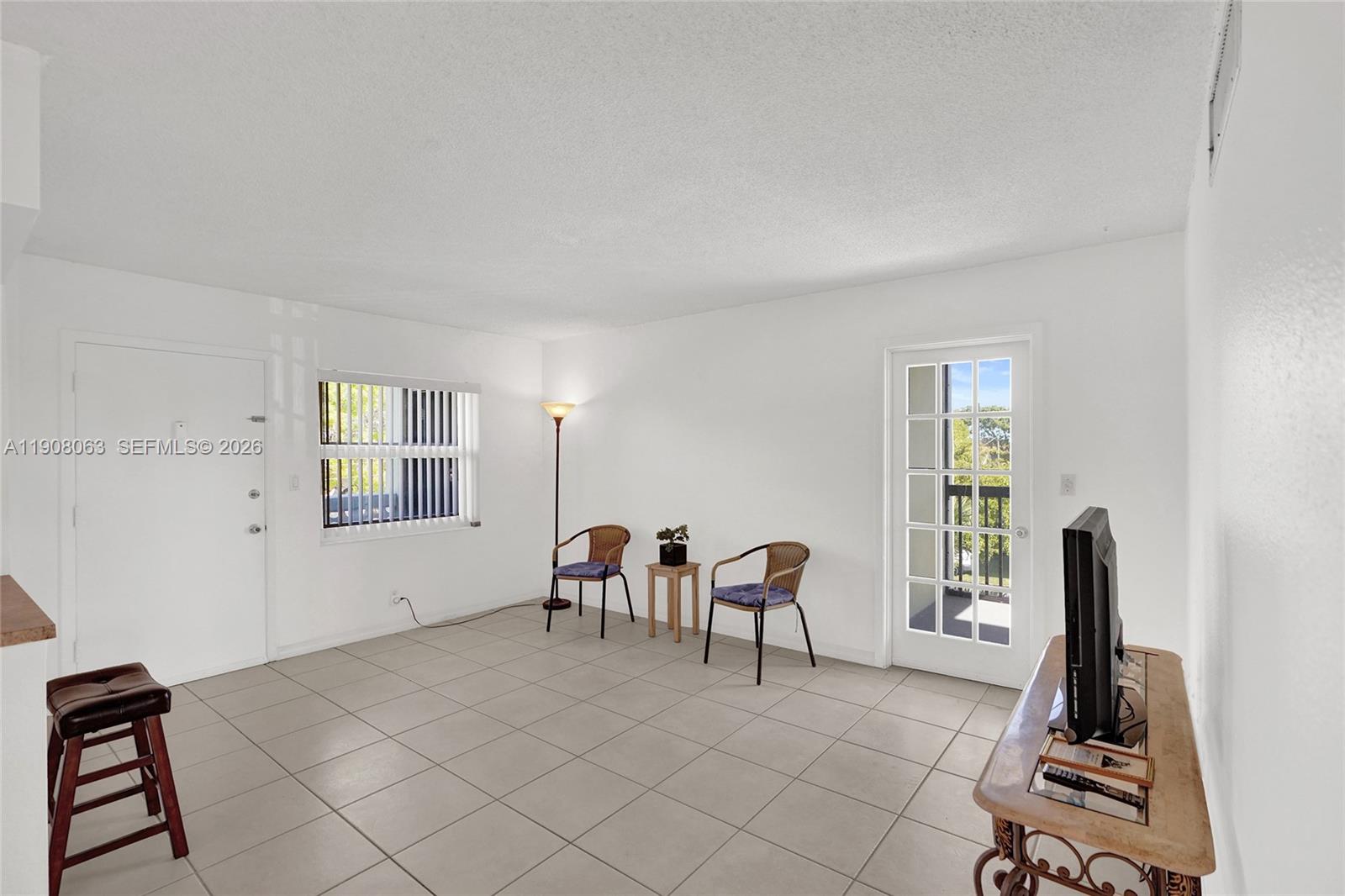 A living room features white walls, tile flooring, two chairs, a small table, and a door — 1425 Arthur St # 301A, Hollywood FL 33020, HOLLYWOOD, FL