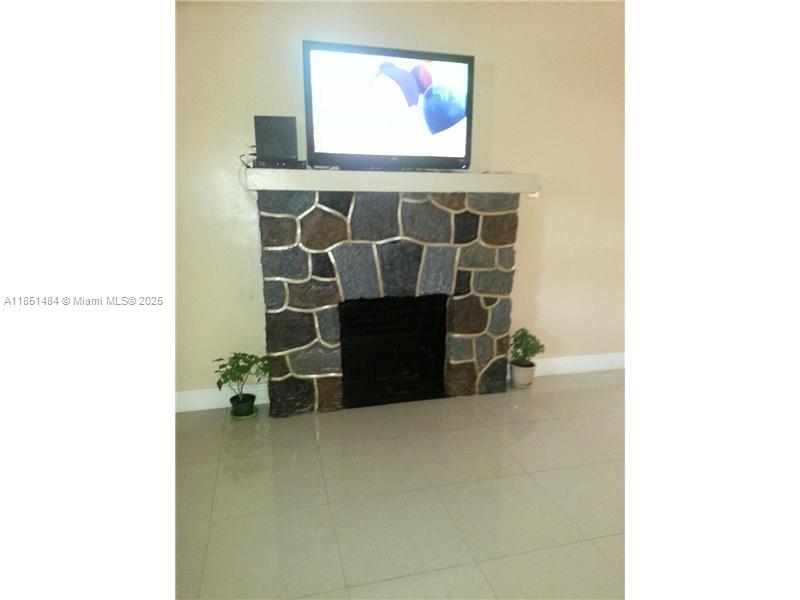 A living room features a stone fireplace with a television mounted on the mantel — 321 NW 13th Ave, Miami FL 33125, MIAMI, FL