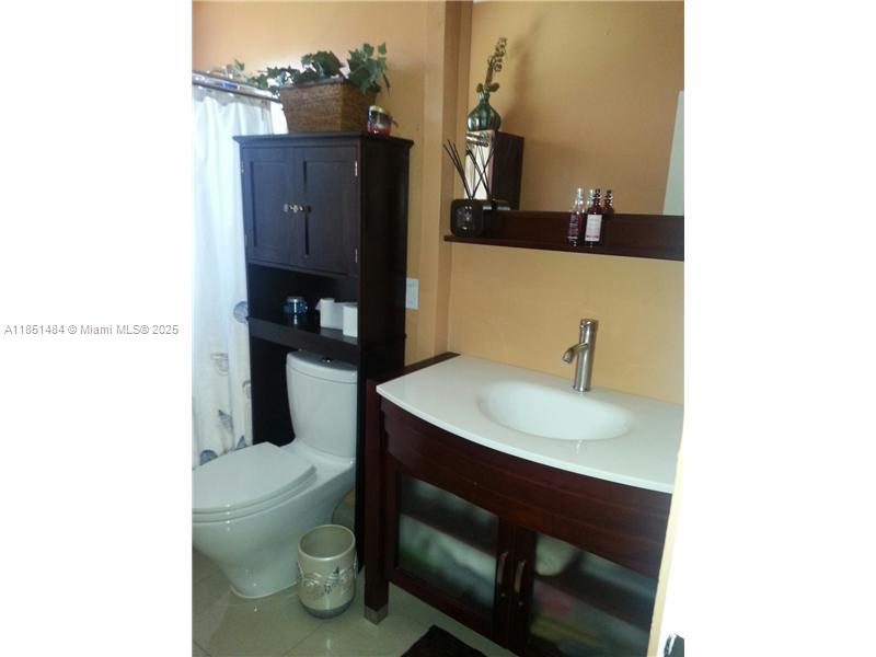 A bathroom features a dark wood vanity with a white countertop and a matching over-toilet cabinet — 321 NW 13th Ave, Miami FL 33125, MIAMI, FL