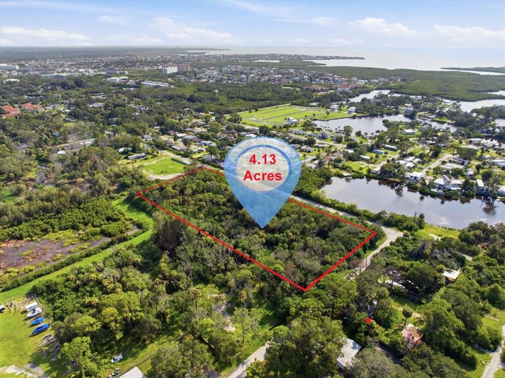 An aerial view shows a rectangular, wooded 4.13-acre plot of land outlined in red — 6814 OELSNER STREET, NEW PORT RICHEY, FL