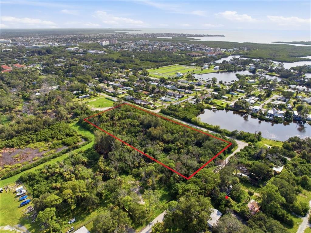 An aerial view shows a rectangular plot of undeveloped land outlined in red near water — 6814 OELSNER STREET, NEW PORT RICHEY, FL