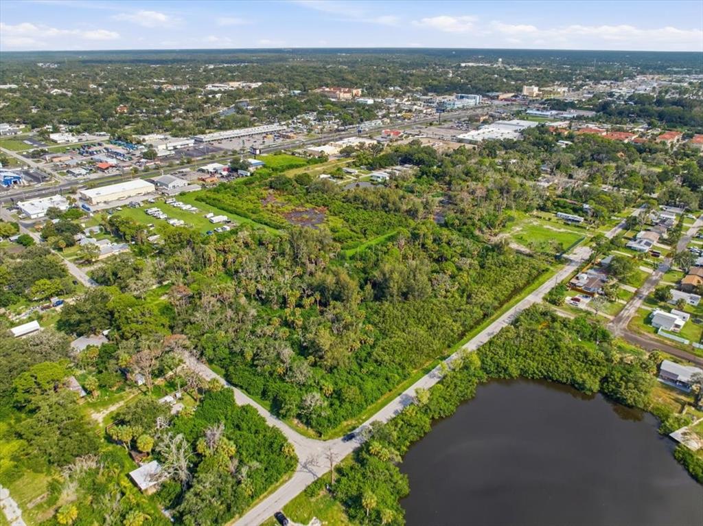 An aerial view shows a wooded lot adjacent to a pond and a residential street — 6814 OELSNER STREET, NEW PORT RICHEY, FL