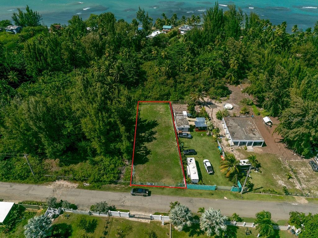 An aerial view shows a rectangular vacant lot outlined in red next to a house — PR 968 Km. 2.0, LAS PICUA PR 968 KM. 2.0, LOT 18A, PUNTA ARENA, LAS PICUAS UNIT 18A, RIO GRANDE, PR