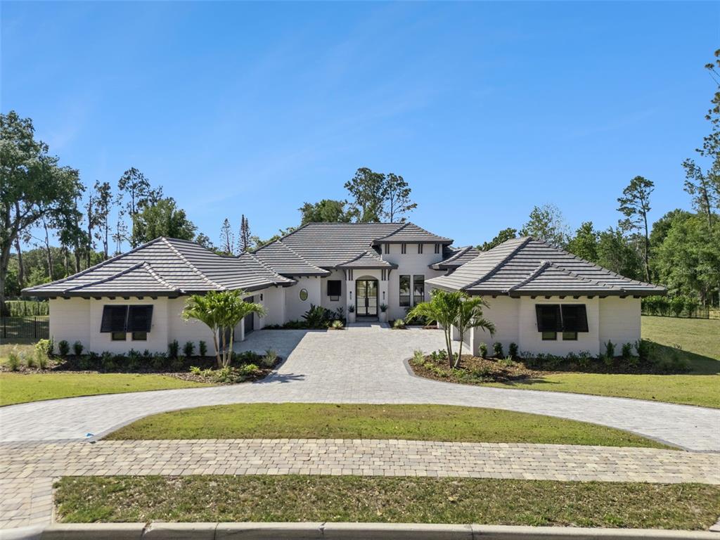 A single-story house with a tiled roof, white stucco exterior, and a paved circular driveway — 16989 LUCCA LANE, MONTVERDE, FL