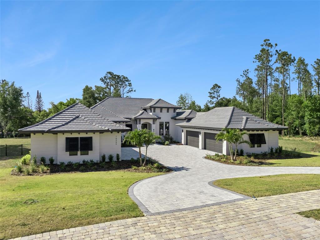 A single-story house with a gray tile roof, white stucco exterior, and a paved driveway — 16989 LUCCA LANE, MONTVERDE, FL