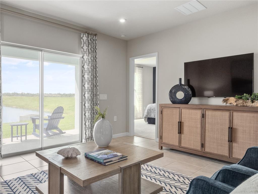 A living room features a wooden media console, coffee table, and sliding doors to a patio — 1258 TURTLE ISLAND ROAD, LADY LAKE, FL