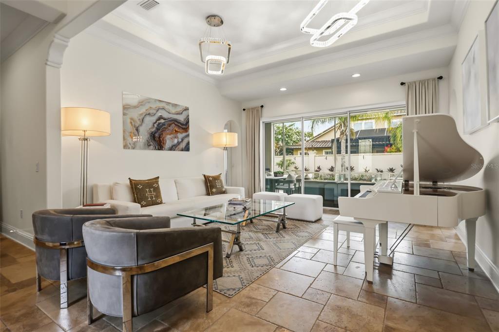 A living room features a white grand piano, a sofa, two armchairs, and tile flooring — 12417 MONTALCINO CIRCLE, WINDERMERE, FL