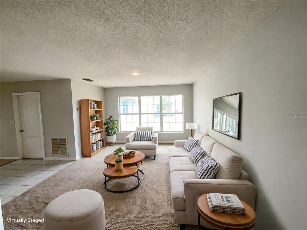 A living room with a beige sofa, two nested coffee tables, and a wooden bookshelf — 724 HARLAND COURT, KISSIMMEE, FL