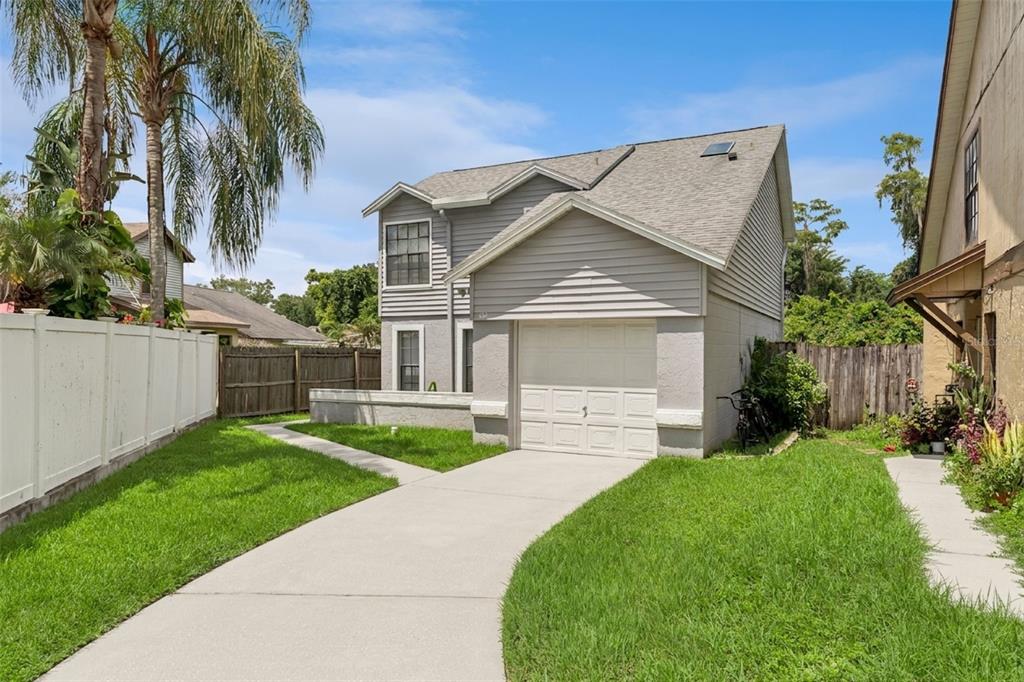 A two-story gray house with a single-car garage, concrete driveway, and a fenced front yard — 533 MADRIGAL COURT, ORLANDO, FL