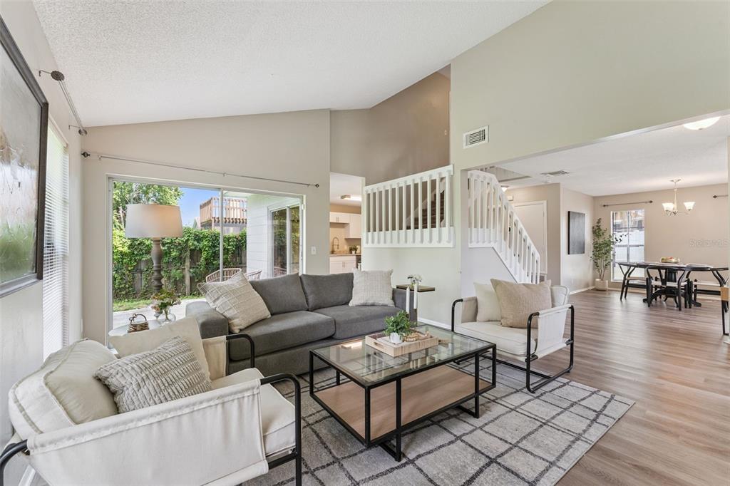 A living room with a gray sofa, two armchairs, a glass coffee table, and stairs — 533 MADRIGAL COURT, ORLANDO, FL